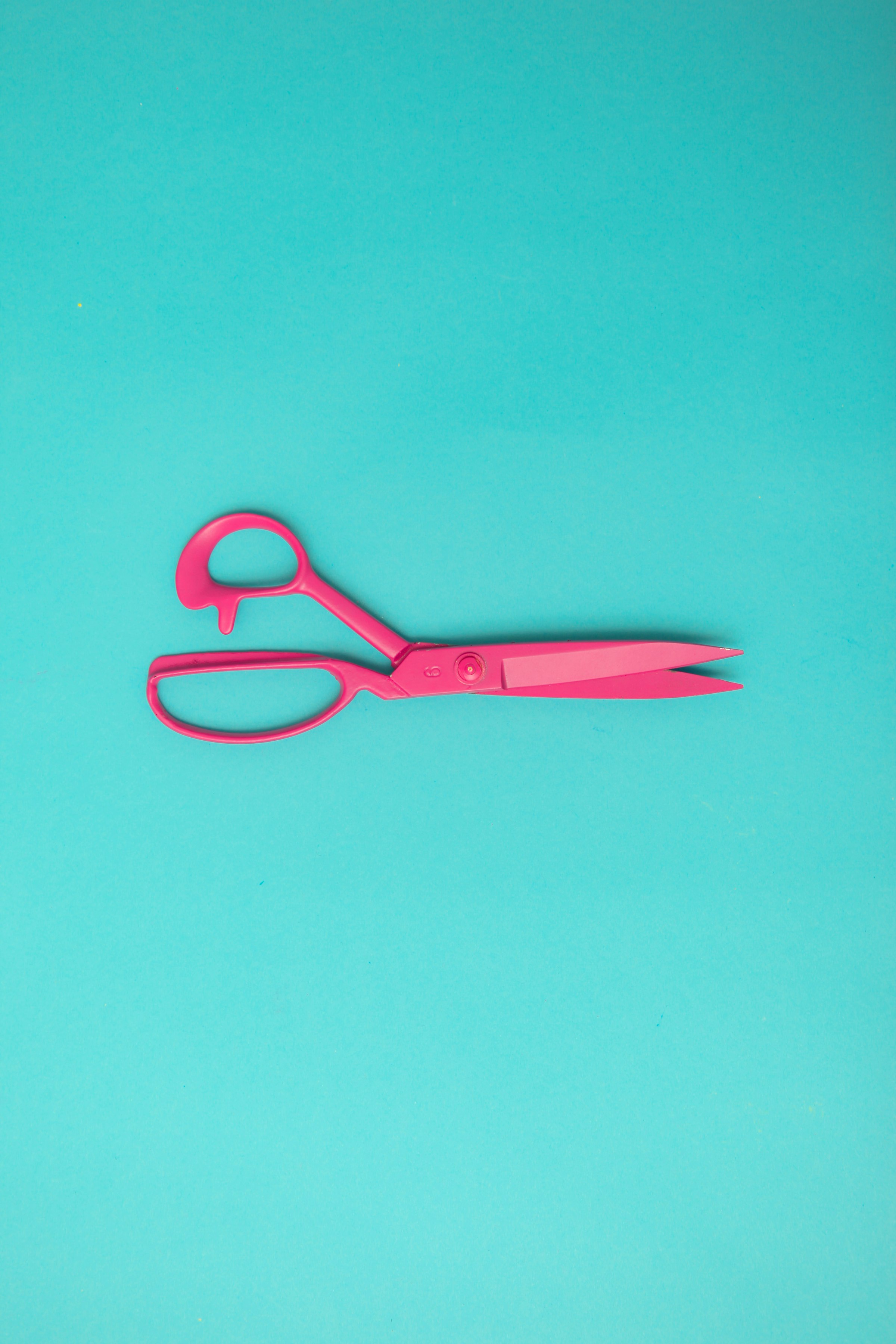 Red handled scissors resting on a vibrant blue surface