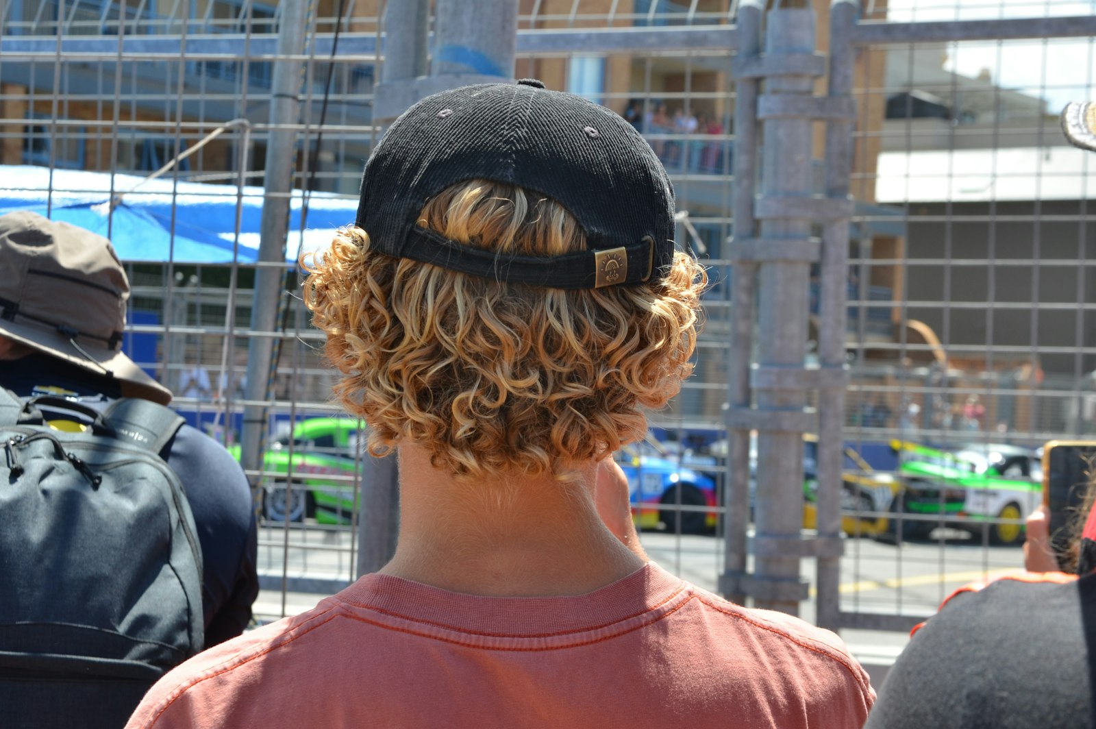 Curly-haired person wearing a hat and looking to the side