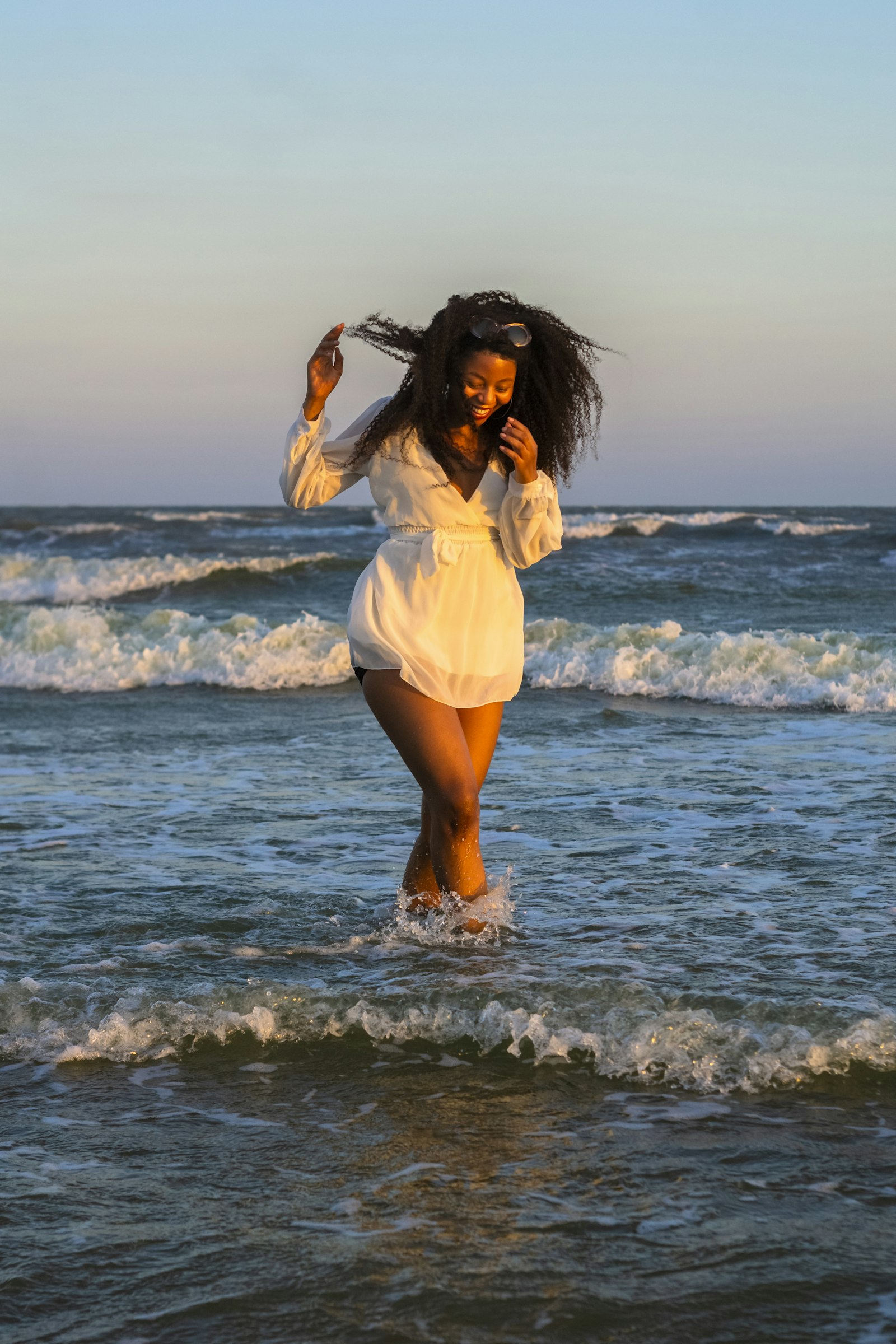 Woman with springy coils standing near the ocean