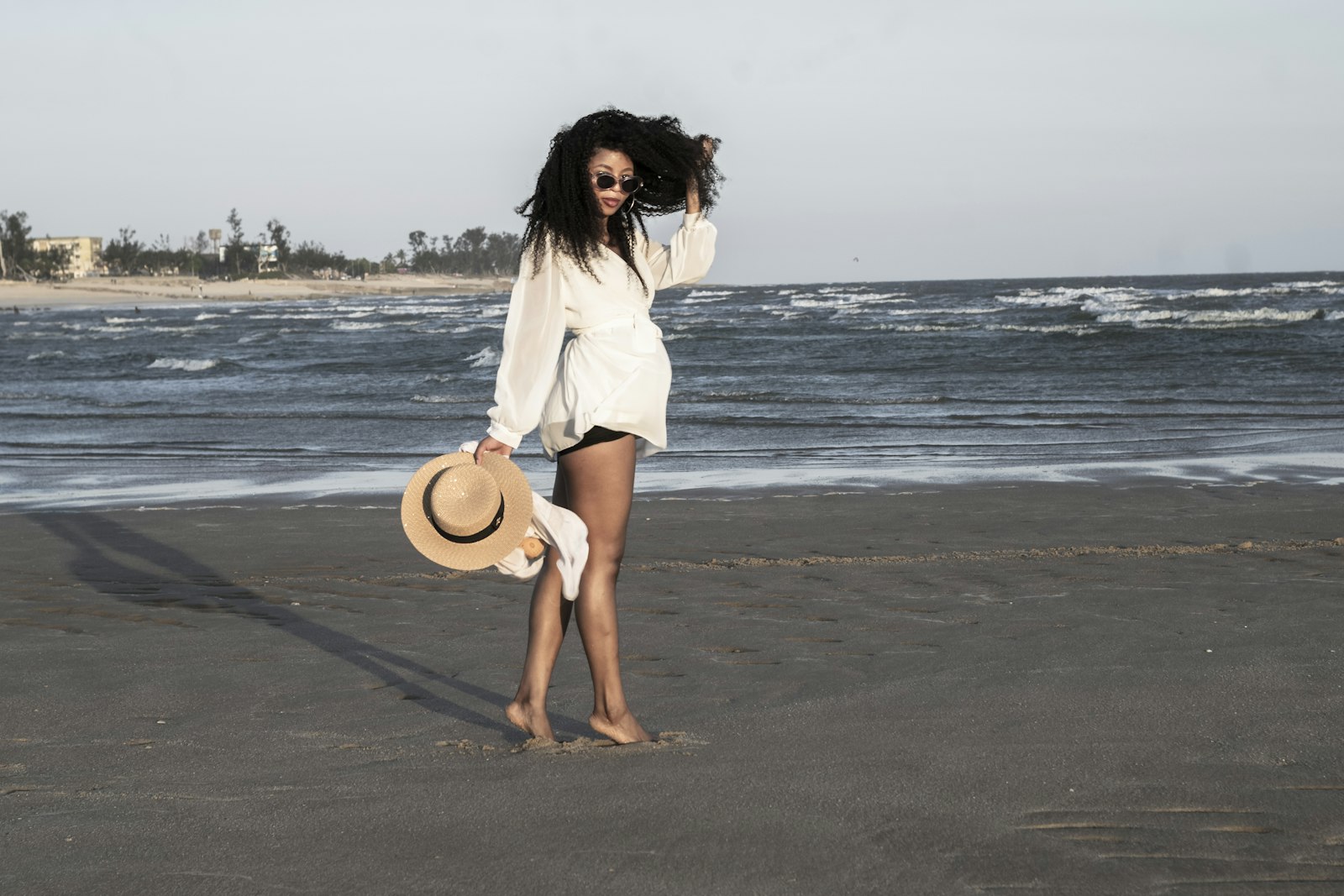 Woman holding a hat with tight zigzag coils blowing in the wind