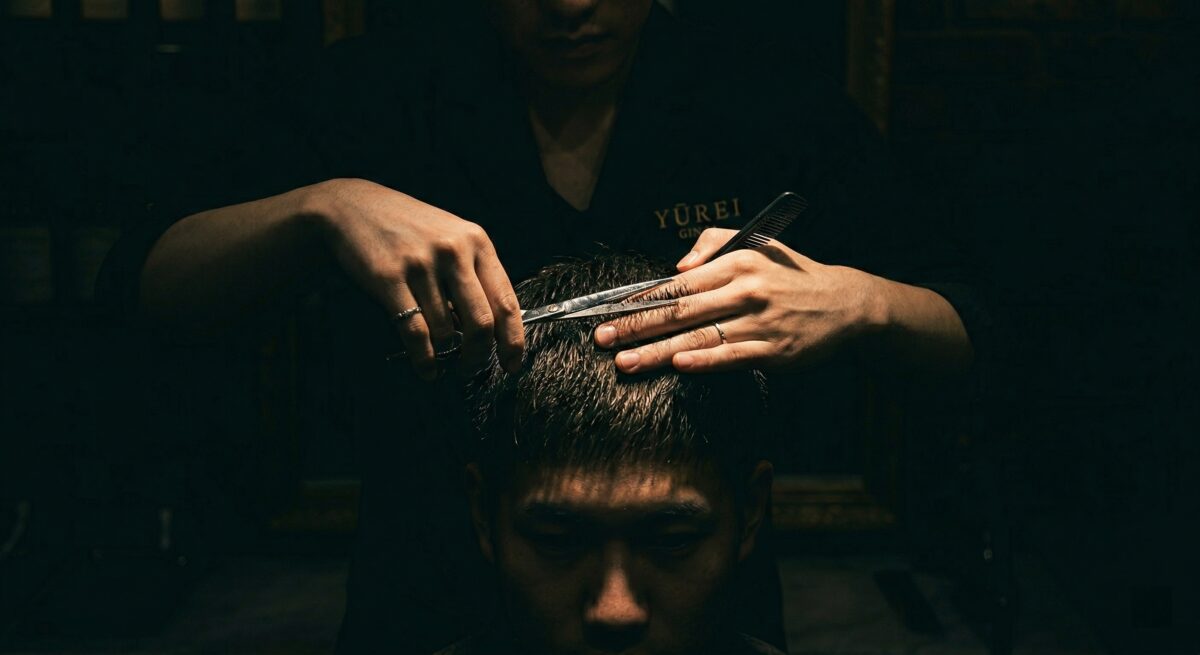Professional barber cutting customer hair with dark studio dramatic lighting