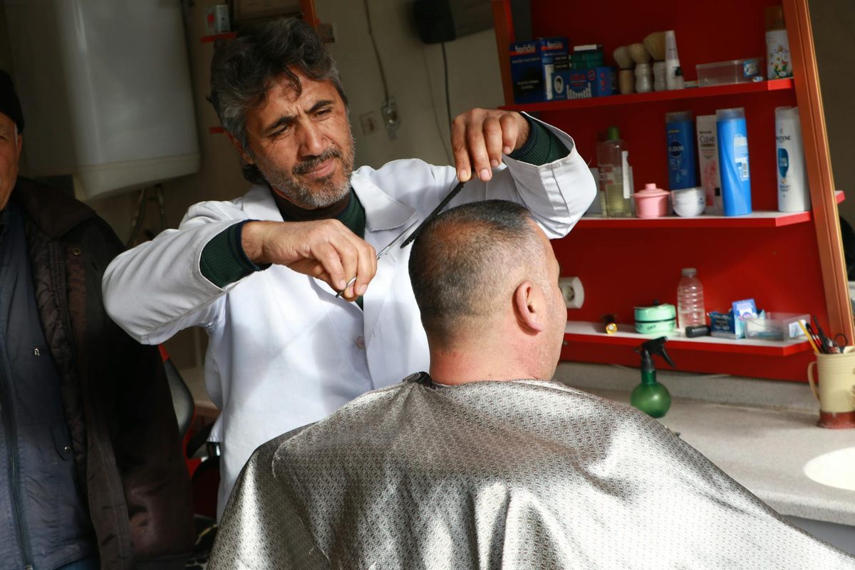 Barber cutting customer hair with professional technique