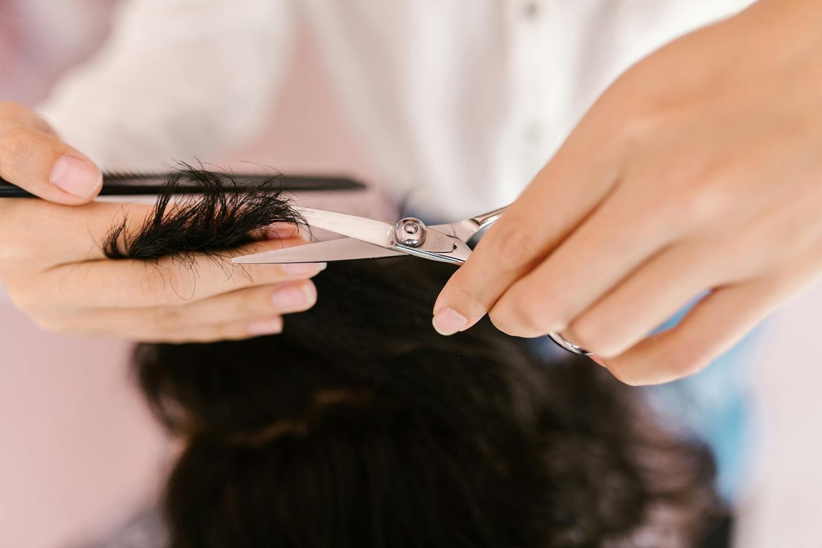 Close-up hands cutting hair with professional scissors