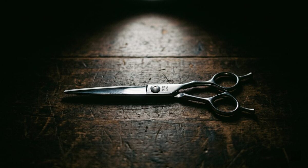 Professional cutting shear on dark wood surface with artistic lighting