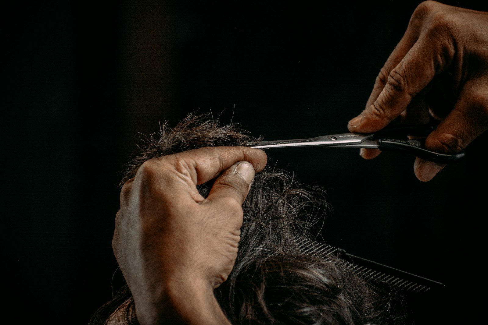 Stylist working carefully through a client’s long hair with scissors