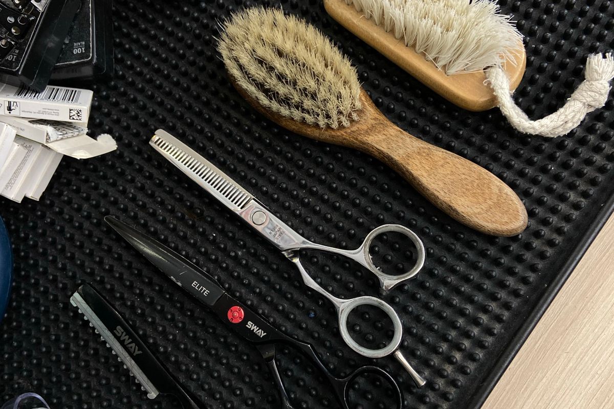 Erineva pikkusega lõike- ja harvenduskäärid toetuvad kammidega mustale salongimati peale.